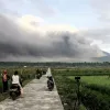 El Monte Semeru arroja materiales volcánicos al aire mientras la gente observa durante una erupción en Lumajang, Java Oriental, Indonesia.