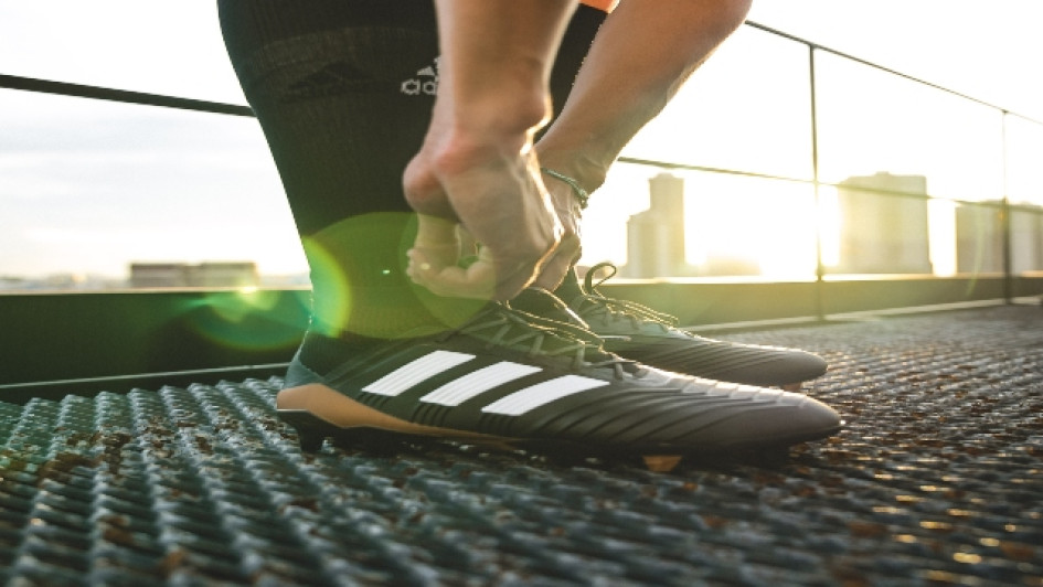 Mejores guayos Adidas del mercado. Hombre se amarra los cordones de sus guayos Adidas.