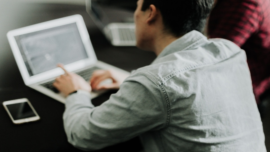 Hombre consulta algo en un computador portatil.
