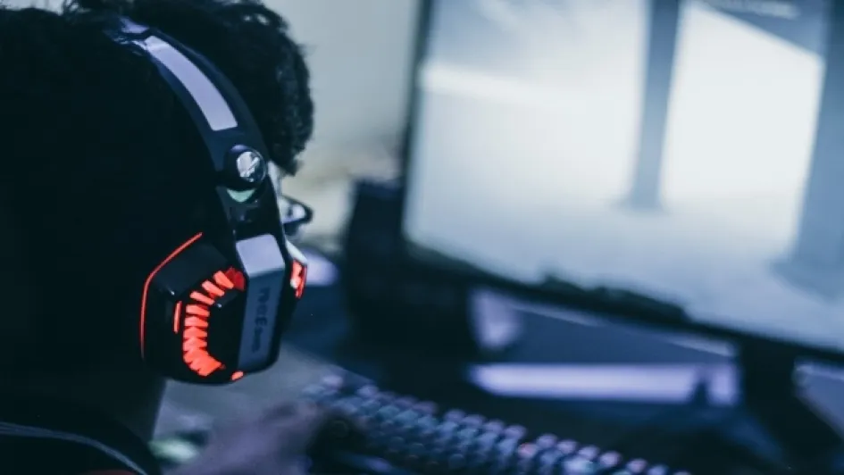 Mejores-audifonos-gamer Persona con audífonos gamer jugando videojuegos en el computador.