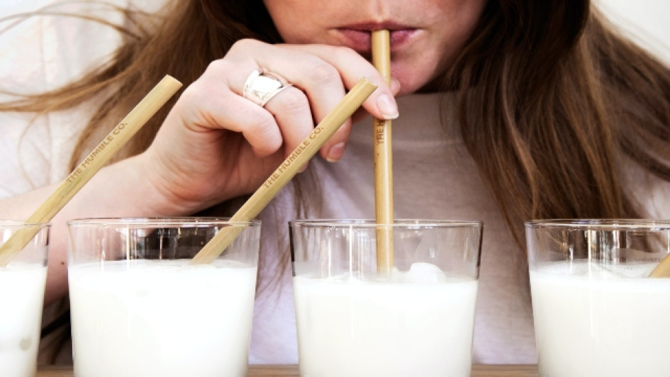 se-puede-tomar-leche-durante-el-ayuno-intermitente Mujer bebe leche de un vaso con un pitillo que sostiene con una mano.