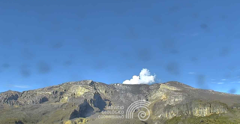 Así lucía en la mañana de este jueves el volcán Nevado del Ruiz desde el cañón del río Azufrado y el cerro Piraña. Se aprecia que el lente de la cámara del Servicio Geológico Colombiano está manchado por la ceniza volcánica.