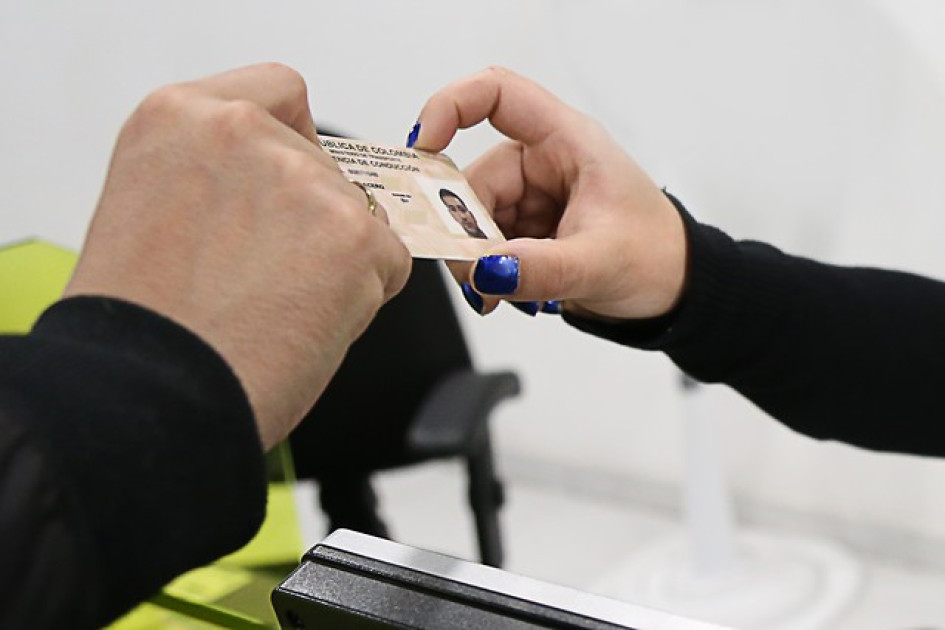 Mano masculina y otra femenina sostienen una licencia de conducción.