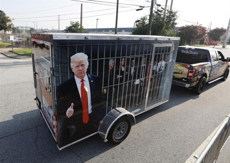 Un partidario del expresidente estadounidense Donald Trump remolcó una celda improvisada que contiene representaciones de líderes demócratas, afuera de la entrada de la cárcel del condado de Fulton, antes de la llegada de Trump para entregarse a las autoridades después de una acusación contra él y 18 personas más de interferencia electoral del 2020 en Atlanta (Georgia). Un partidario del expresidente estadounidense Donald Trump remolcó una celda improvisada que contiene representaciones de líderes demócratas, afuera de la entrada de la cárcel del condado de Fulton, antes de la llegada de Trump para entregarse a las autoridades después de una acusación contra él y 18 personas más de interferencia electoral del 2020 en Atlanta (Georgia).