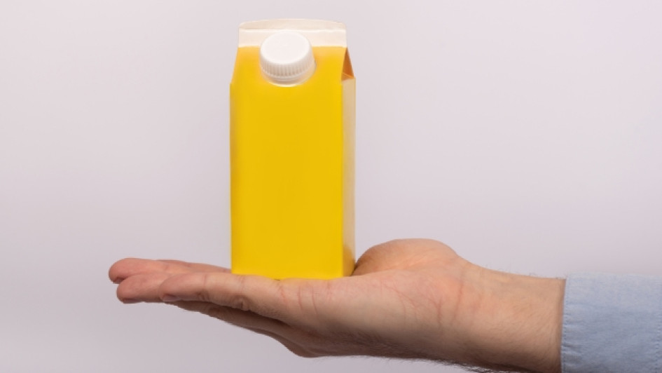 Como-abrir-una-caja-de-leche Mano sosteniendo una caja de leche amarilla.