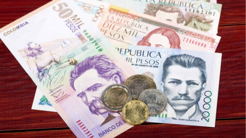 Como-calcular-los-intereses-de-las-cesantias Billetes y monedas de plata colombiana en una mesa de madera.