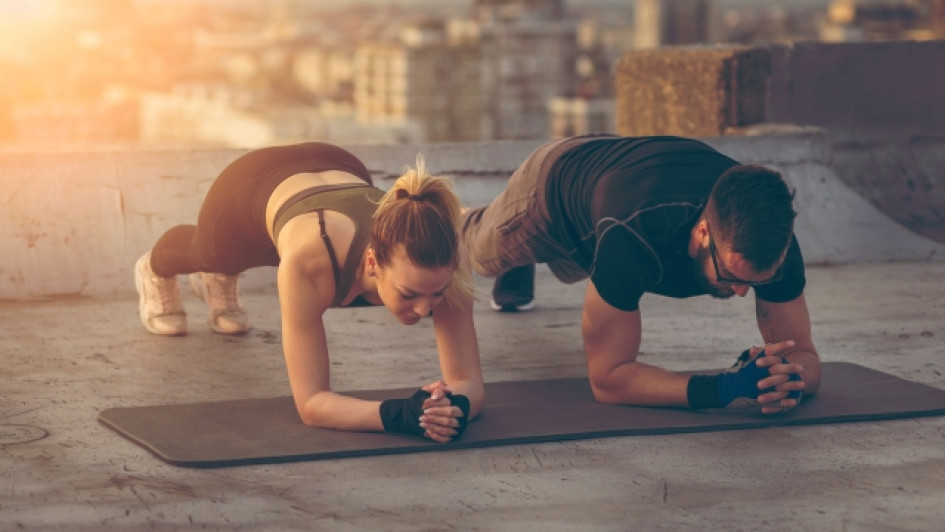 Ejercicios-para-desarrollar-fuerza-muscular Hombre y mujer realizando planchas en una azotea de un edificio.