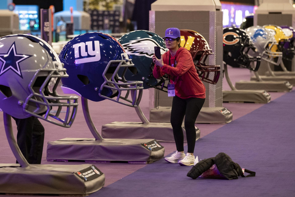 Una mujer toma una fotografía de cascos de fútbol de gran tamaño en la experiencia del Super Bowl en el Centro de Convenciones Mandalay Bay South en Las Vegas, Nevada, EE.UU. Una mujer toma una fotografía de cascos de fútbol de gran tamaño en la experiencia del Super Bowl en el Centro de Convenciones Mandalay Bay South en Las Vegas, Nevada, EE.UU.