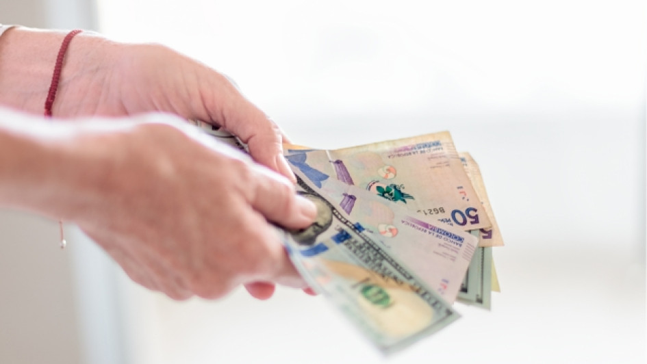 Bancos-que-prestan-dinero-a-reportados Manos sosteniendo billetes de pesos colombianos y dólares americanos.