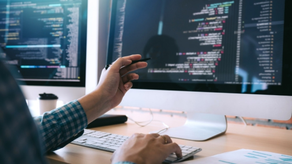 Cuanto-gana-un-desarrollador-de-software-en-colombia Persona en frente a tres pantallas realizando operaciones en código