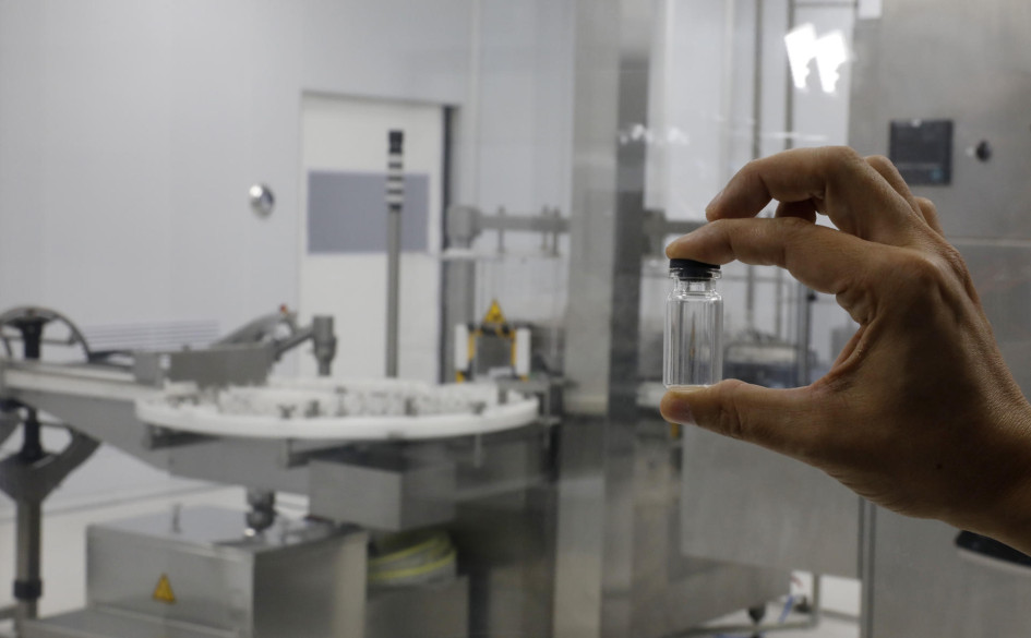 Envase de vacuna Un hombre sostiene un envase de una vacuna en la planta de producción de vacunas VaxThera