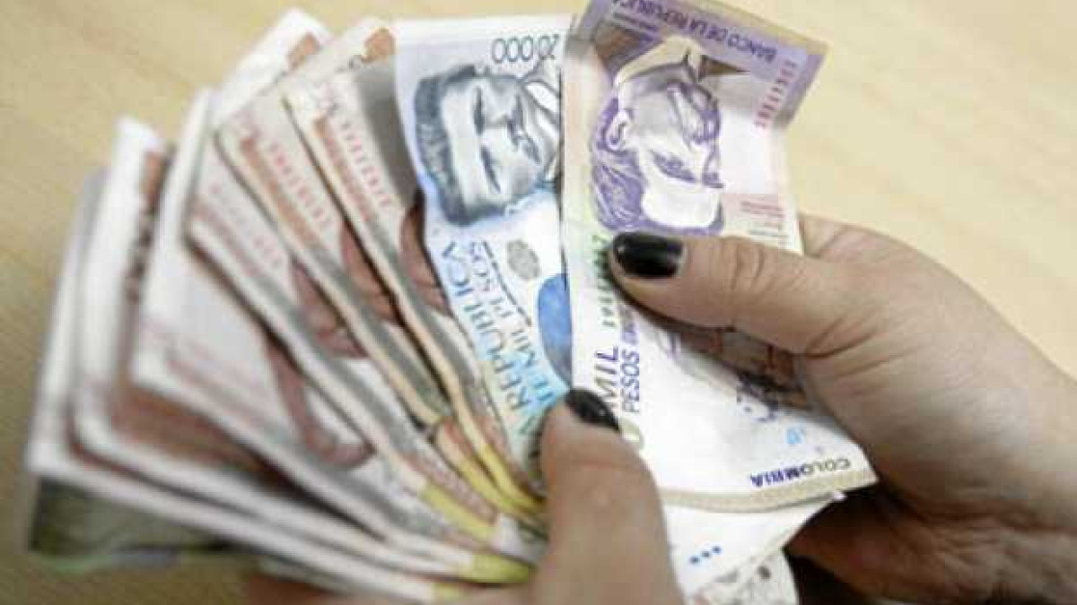 Persona contando billetes de pesos colombianos.