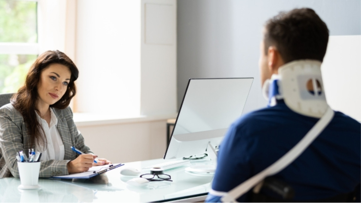 Mujer atiende a un hombre que usa un cuello ortopédico y un yeso.
