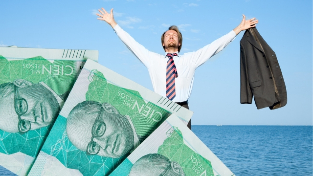 Hombre con traje en una playa levantando las manos. Billetes de 100.000 pesos colombianos al frente.