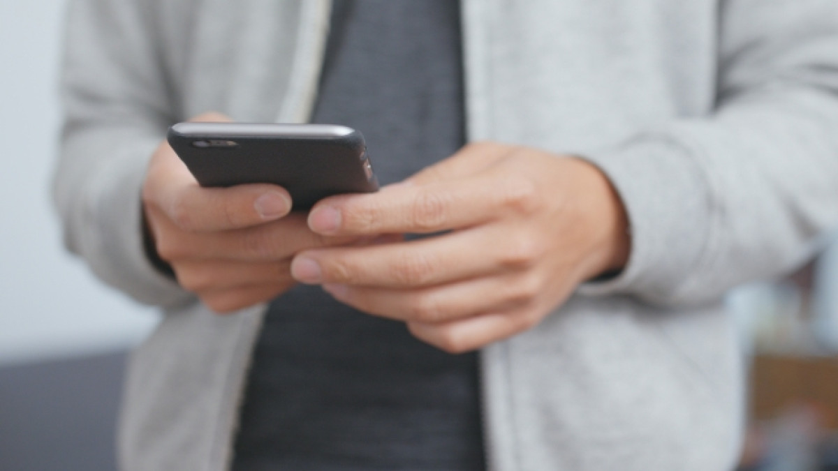 Hombre sosteniendo un celular con ambas manos.