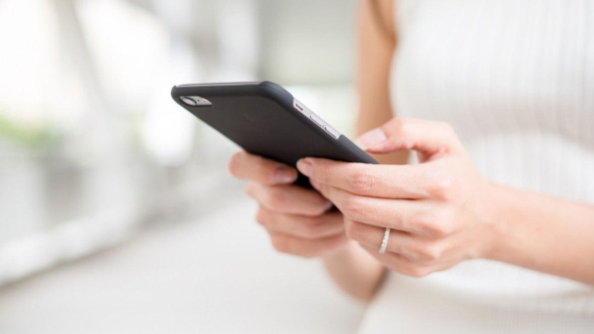 Mujer sosteniendo su teléfono celular.