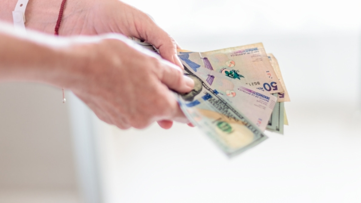 Manos sosteniendo billetes de pesos colombianos.