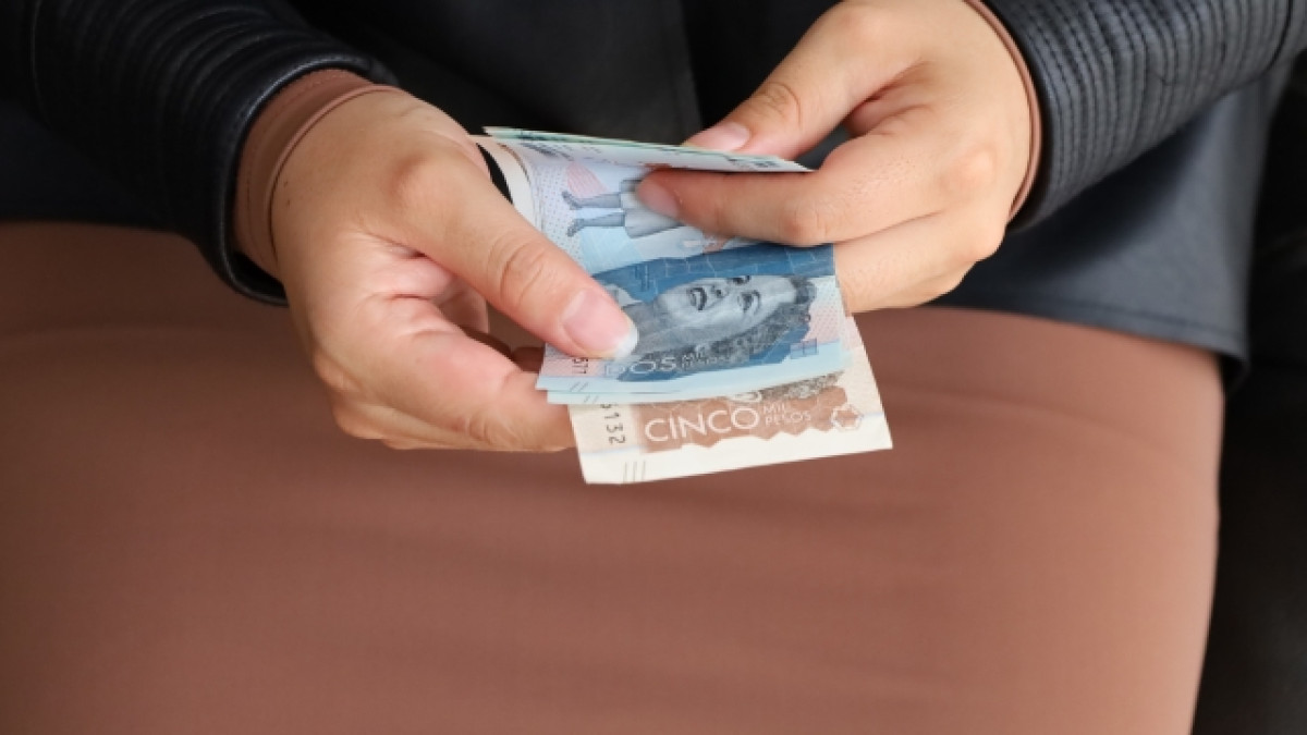 Mano sosteniendo billetes de Colombia