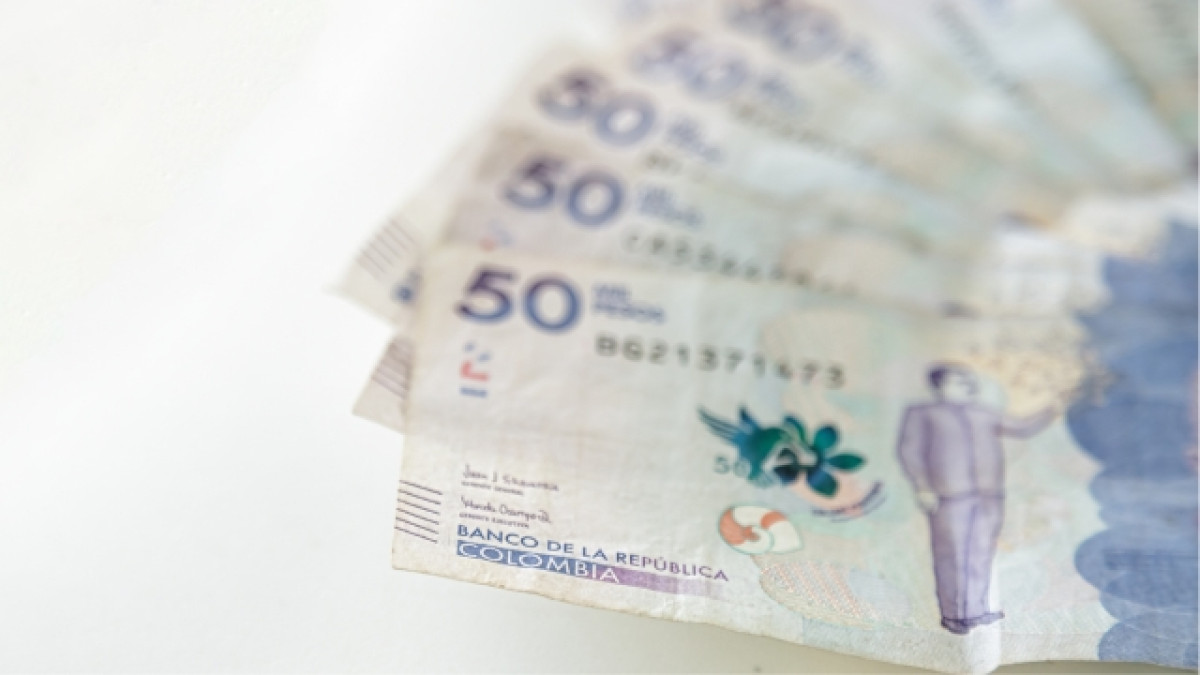 Mano sosteniendo billetes de 50 mil pesos colombianos