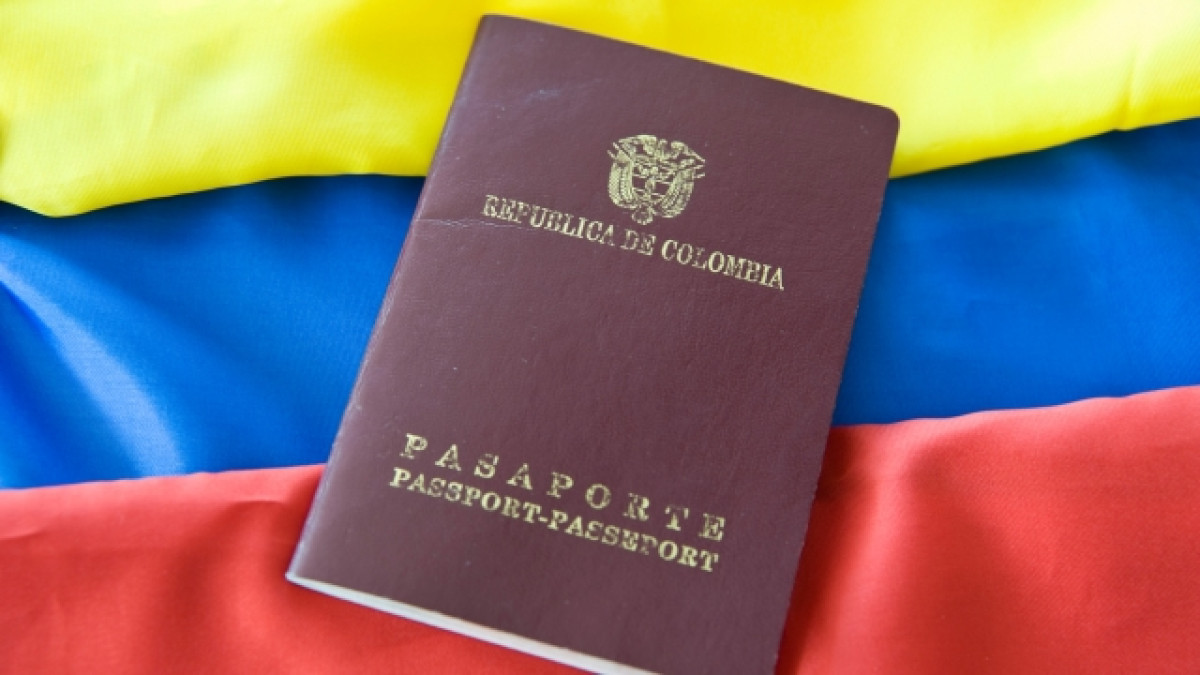 Pasaporte colombiano con una bandera colombiana detrás